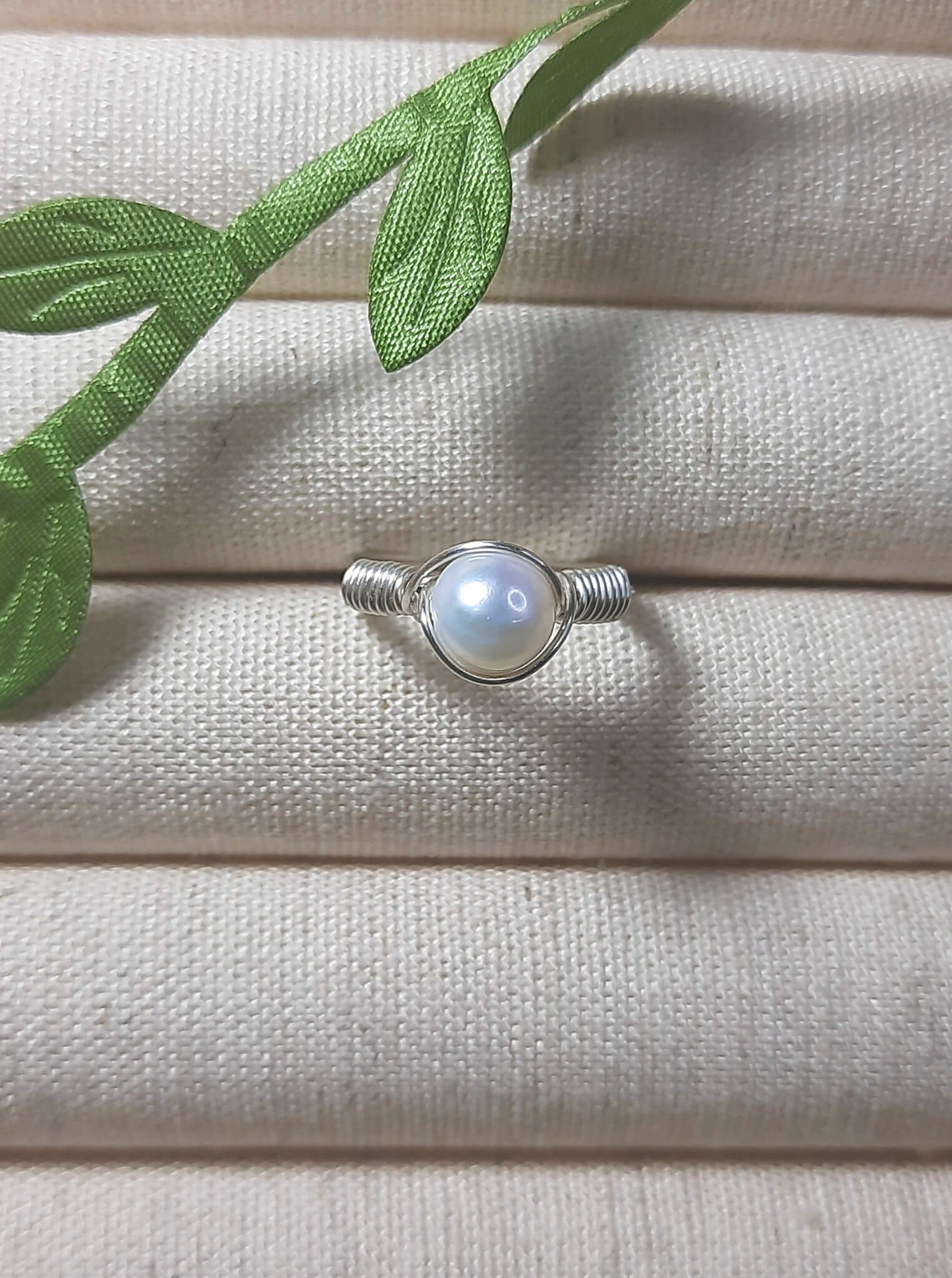 Natural freshwater pearl ring in silver wire wrap on jewelry display, handmade Sri Lankan pearl jewelry for wisdom and calming energy