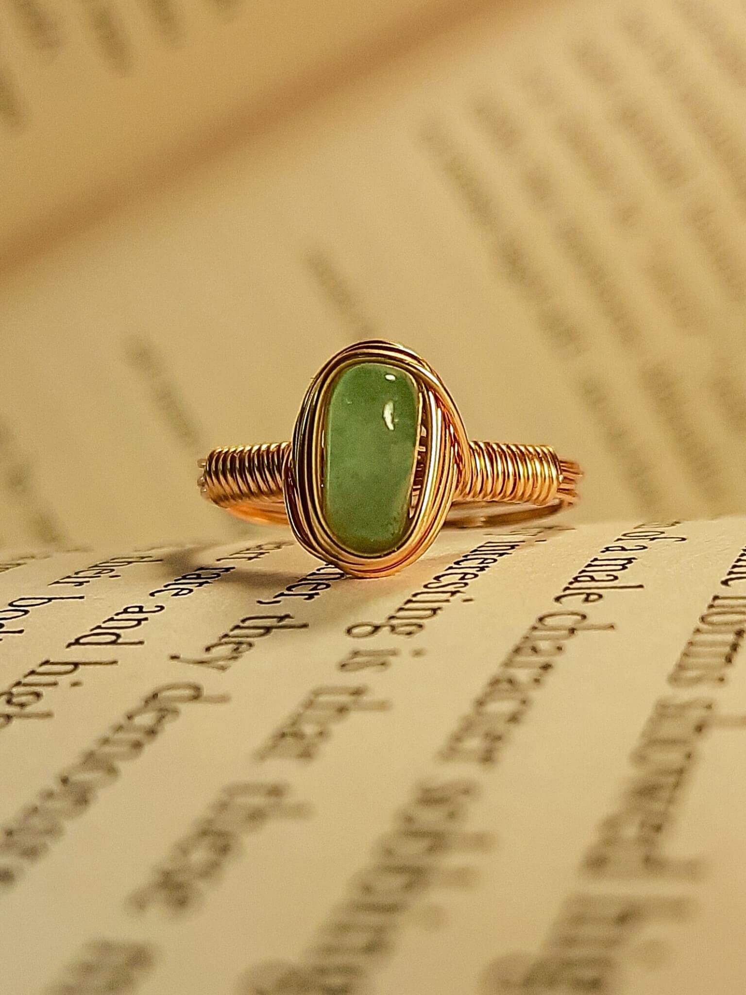 Green aventurine irregular stone ring on vintage book pages showing handmade gold wire wrapped healing crystal jewelry, Sri Lankan spiritual ring featuring natural green gemstone perfect as boho luck stone ring and prosperity amulet for growth and abundance meditation