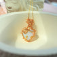 Opalite heart-shaped crystal pendant with detailed gold wire wrap on delicate chain, styled on white surface – handmade necklace by Laganna Sri Lanka

