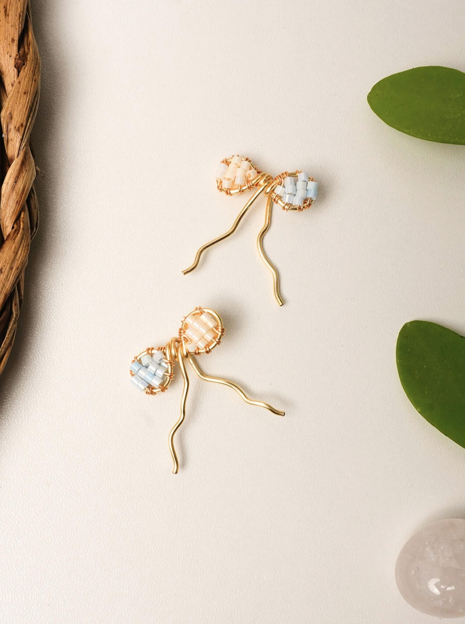 Japanese Miyuki Delica bow earrings handmade with premium glass beads in peach and powder blue, wire-wrapped jewelry by Laganna Sri Lanka, delicate feminine earrings for everyday wear, artisan crafted bow design with graceful wire fall
