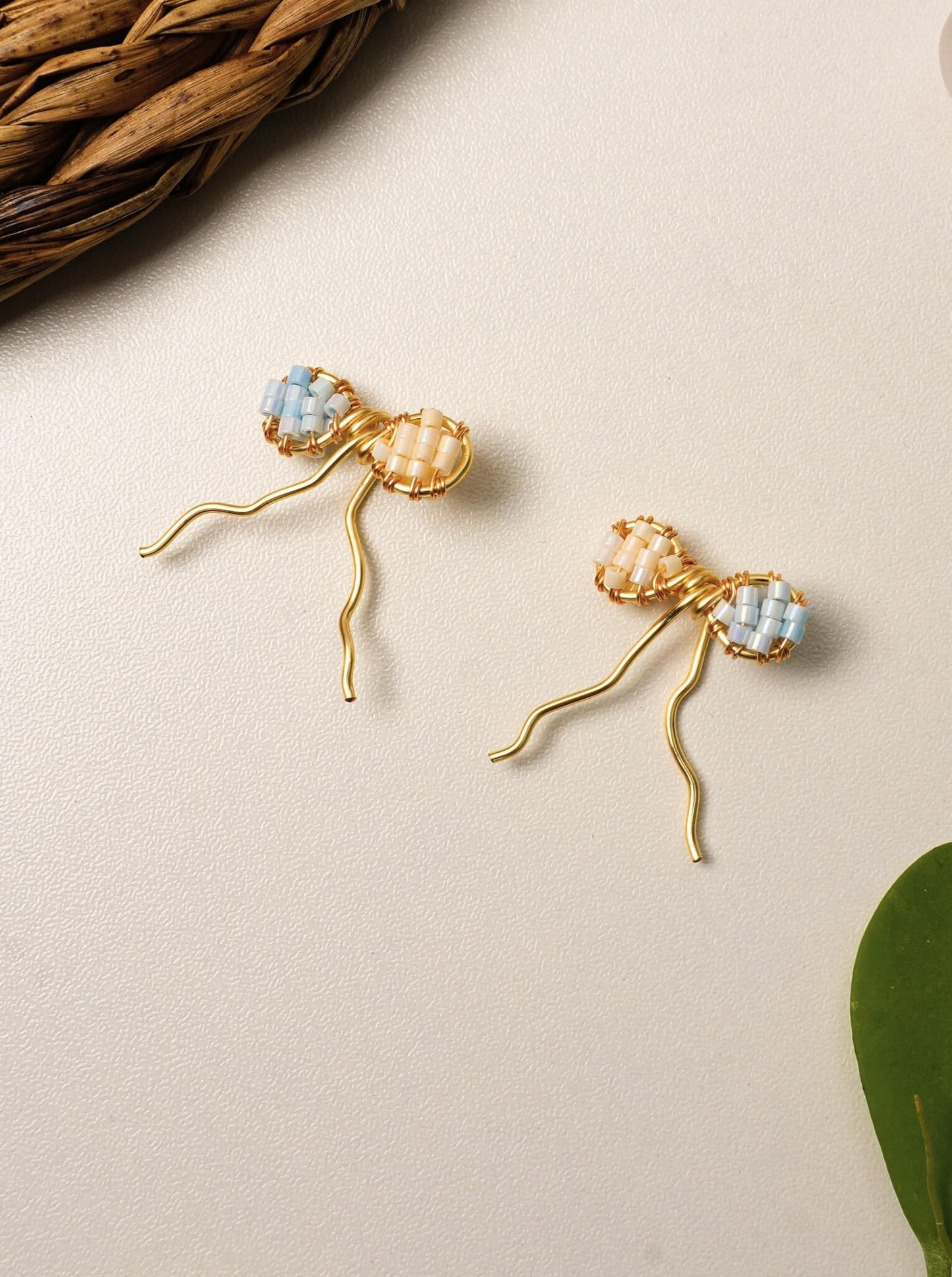 Handmade Japanese Miyuki Delica glass bead bow earrings in soft pastel peach and blue tones, lightweight wire-wrapped artisan jewelry Sri Lanka, dainty bow earrings for women, feminine handcrafted accessories by Laganna