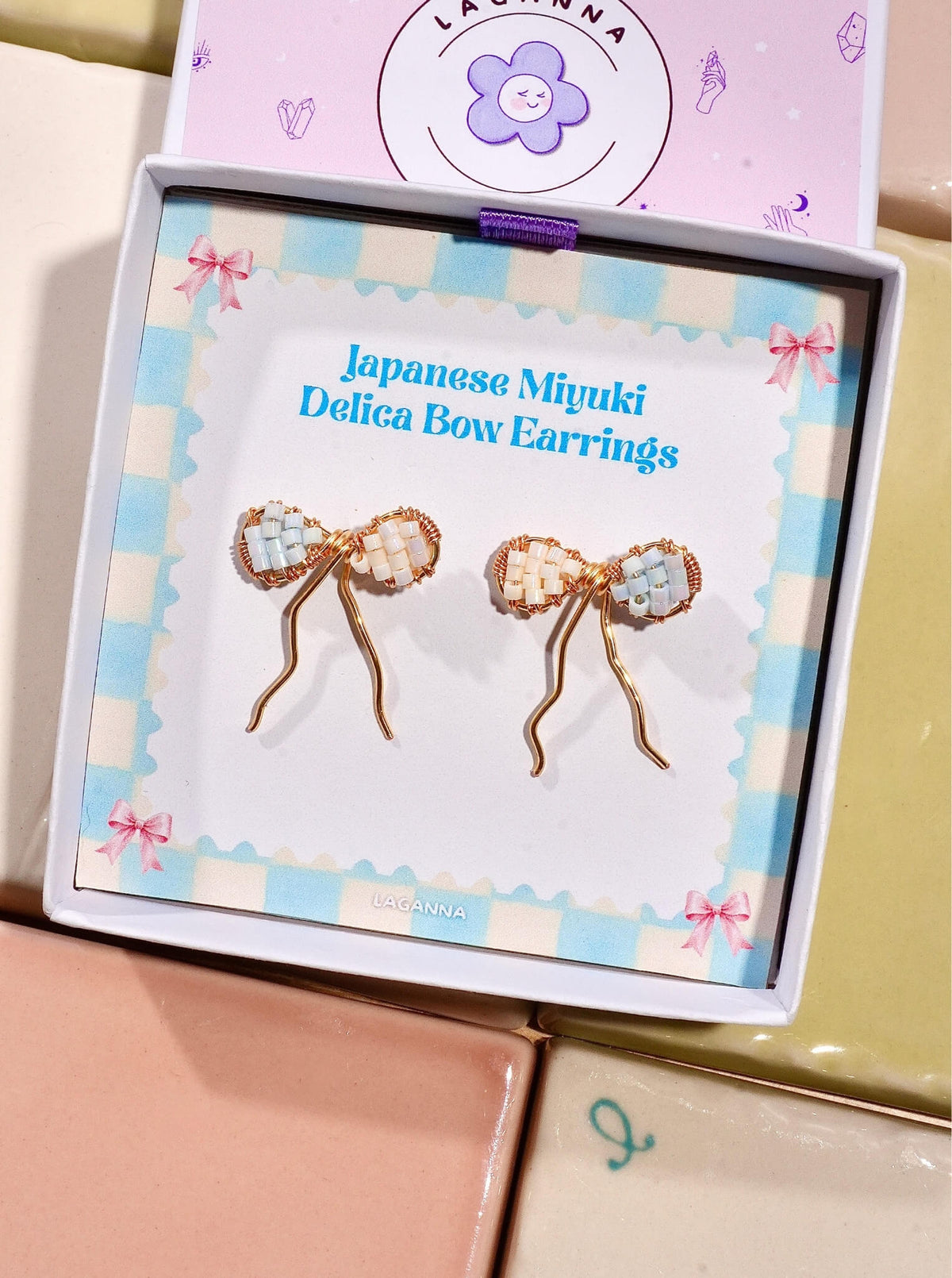 Japanese Miyuki Delica bow earrings in Laganna gift box packaging, handmade wire-wrapped artisan jewelry Sri Lanka, delicate feminine bow design with premium glass beads in powder blue and cream white, lightweight stud earrings for women by Laganna