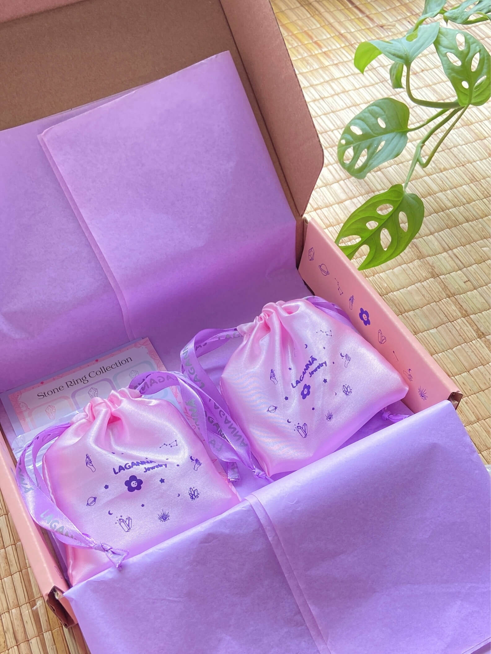 Laganna luxury jewelry gift box with purple tissue paper, celestial-patterned drawstring bags featuring mystical symbols, premium jewelry packaging unboxing experience with branded pouches and stone ring collection card