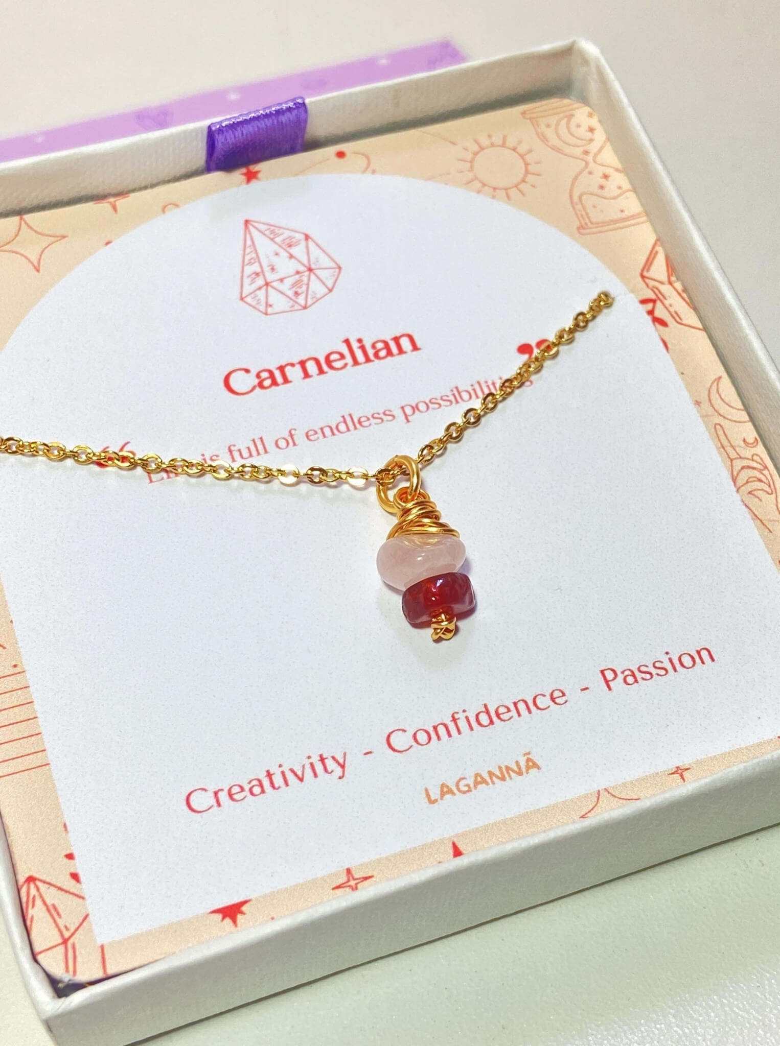 Love Duo irregular stone necklace with rose quartz and carnelian jewelry box closeup side view, handmade Sri Lankan gold wire wrapped dual crystal pendant for love and creativity