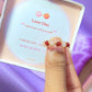 Love Duo braided ring jewelry box held on hand showing rose quartz and carnelian, handmade Sri Lankan gold wire wrapped dual crystal ring gift for self-love