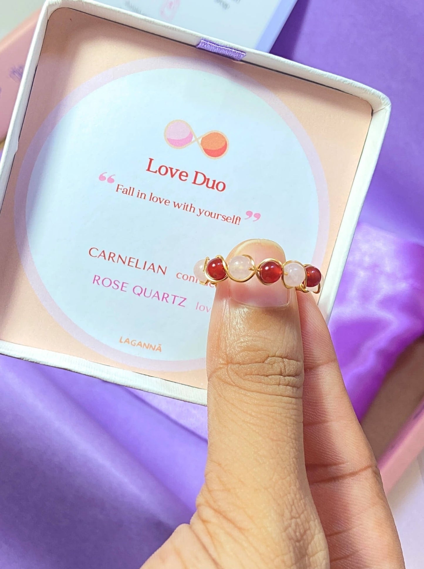 Love Duo braided ring jewelry box held on hand showing rose quartz and carnelian, handmade Sri Lankan gold wire wrapped dual crystal ring gift for self-love