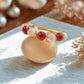  Love Duo braided ring with rose quartz and carnelian on tabletop, handmade Sri Lankan gold wire wrapped dual crystal ring for heart chakra and creativity