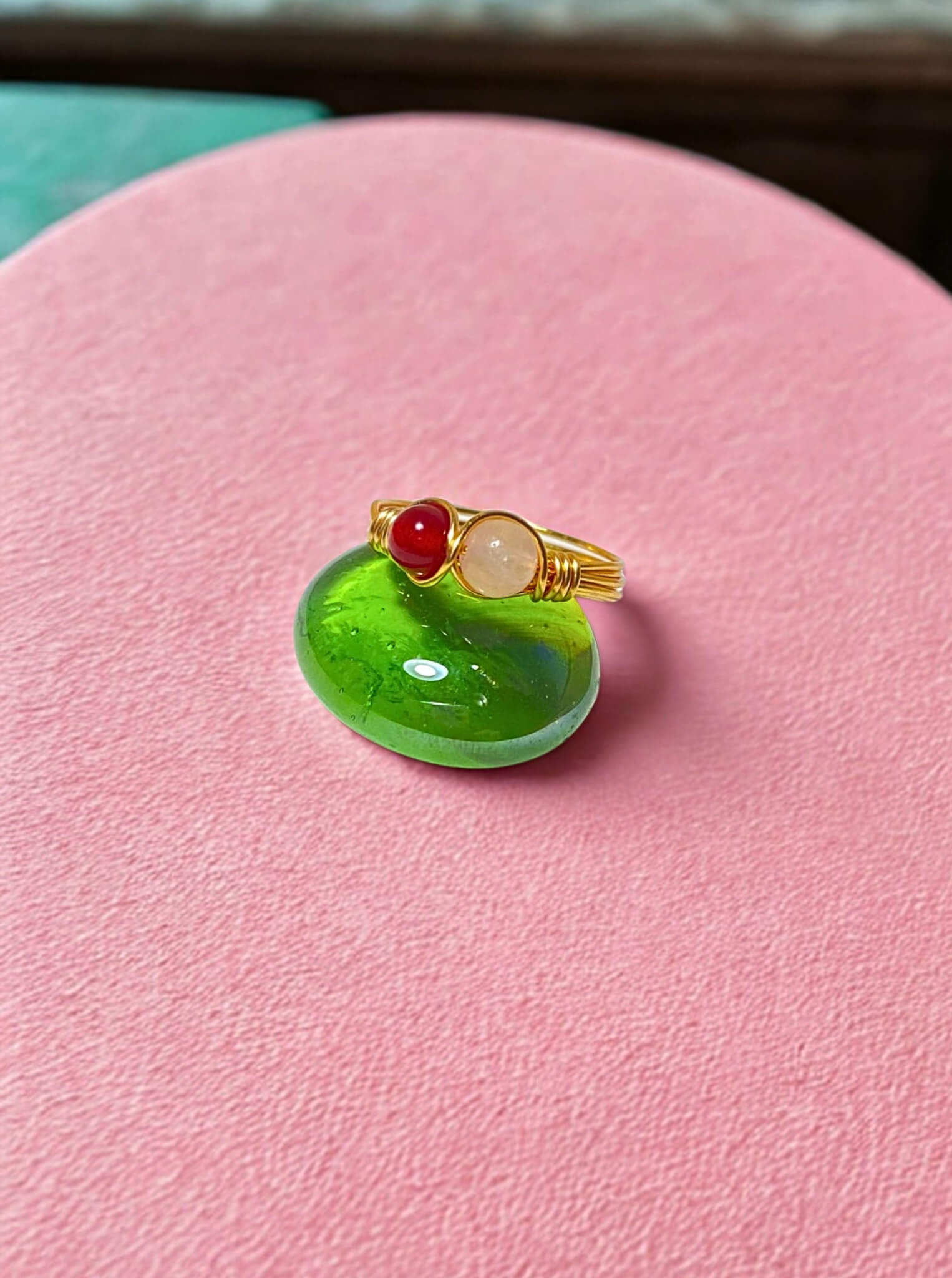 Love Duo ring with rose quartz and carnelian on pink background, handmade Sri Lankan gold wire wrapped dual stone ring for love and creativity