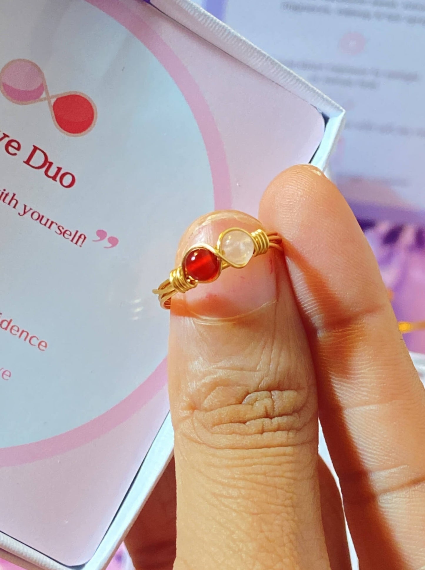 Love Duo ring with rose quartz and carnelian on display - handmade Sri Lankan gold wire-wrapped dual crystal ring for heart chakra, self-love, and creative energy
