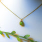 Natural olive jade square stone necklace on jewelry display showing handmade gold wire wrapped healing crystal jewelry, Sri Lankan artisan heart chakra pendant featuring geometric green gemstone perfect as boho abundance necklace and prosperity amulet for meditation and spiritual growth