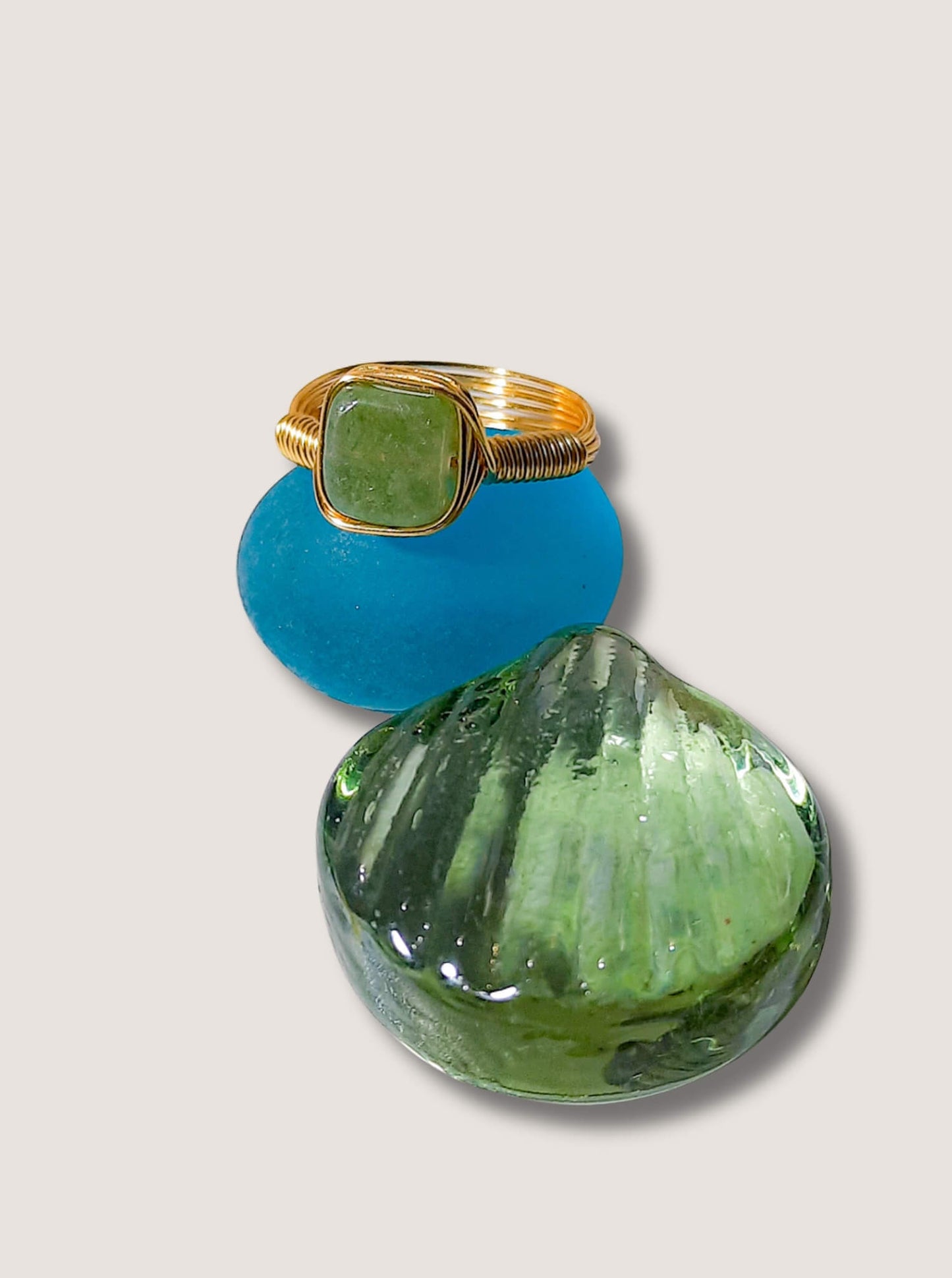 Handmade olive jade square stone ring in gold wire wrap on jewelry display, Sri Lankan healing crystal jewelry for heart chakra balancing and abundance enhancement