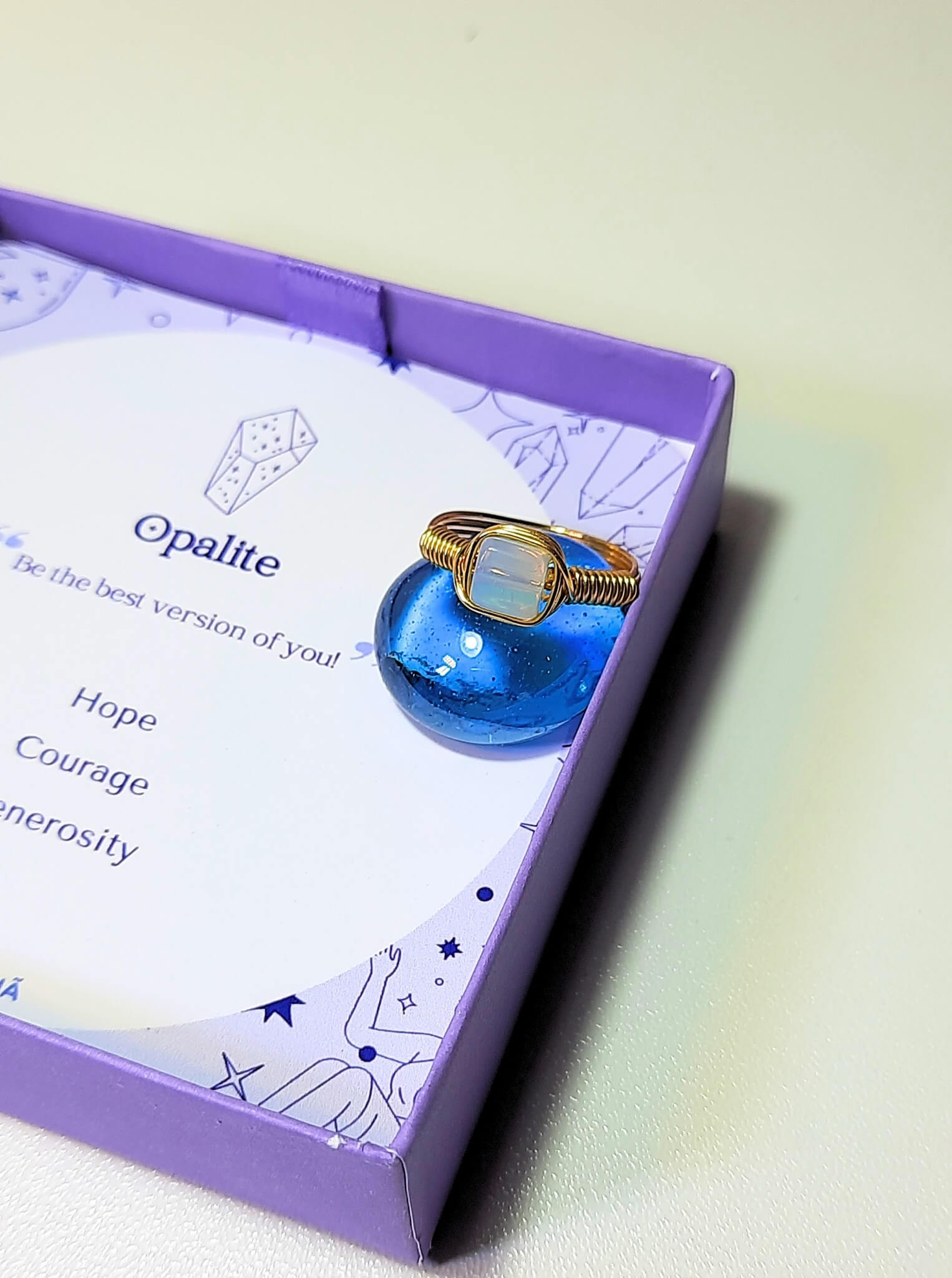 Opalite square stone ring jewelry box on light background, handmade Sri Lankan gold wire wrapped healing crystal ring for clarity and divine connection