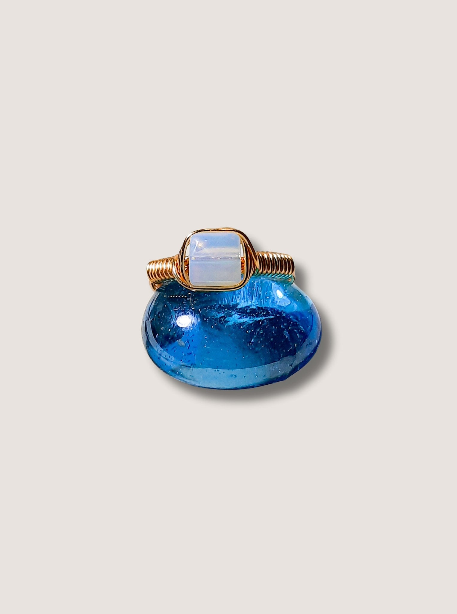 Opalite square stone ring on light background showing gold wire wrapped design, handmade Sri Lankan healing crystal ring for intuition and inner peace