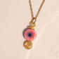 Handmade pink evil eye protection necklace in gold wire wrapped design featuring ceramic evil eye bead and spiral charm, Sri Lankan artisan spiritual jewelry crafted as self-love talisman and protective amulet for women seeking love energy and emotional healing
