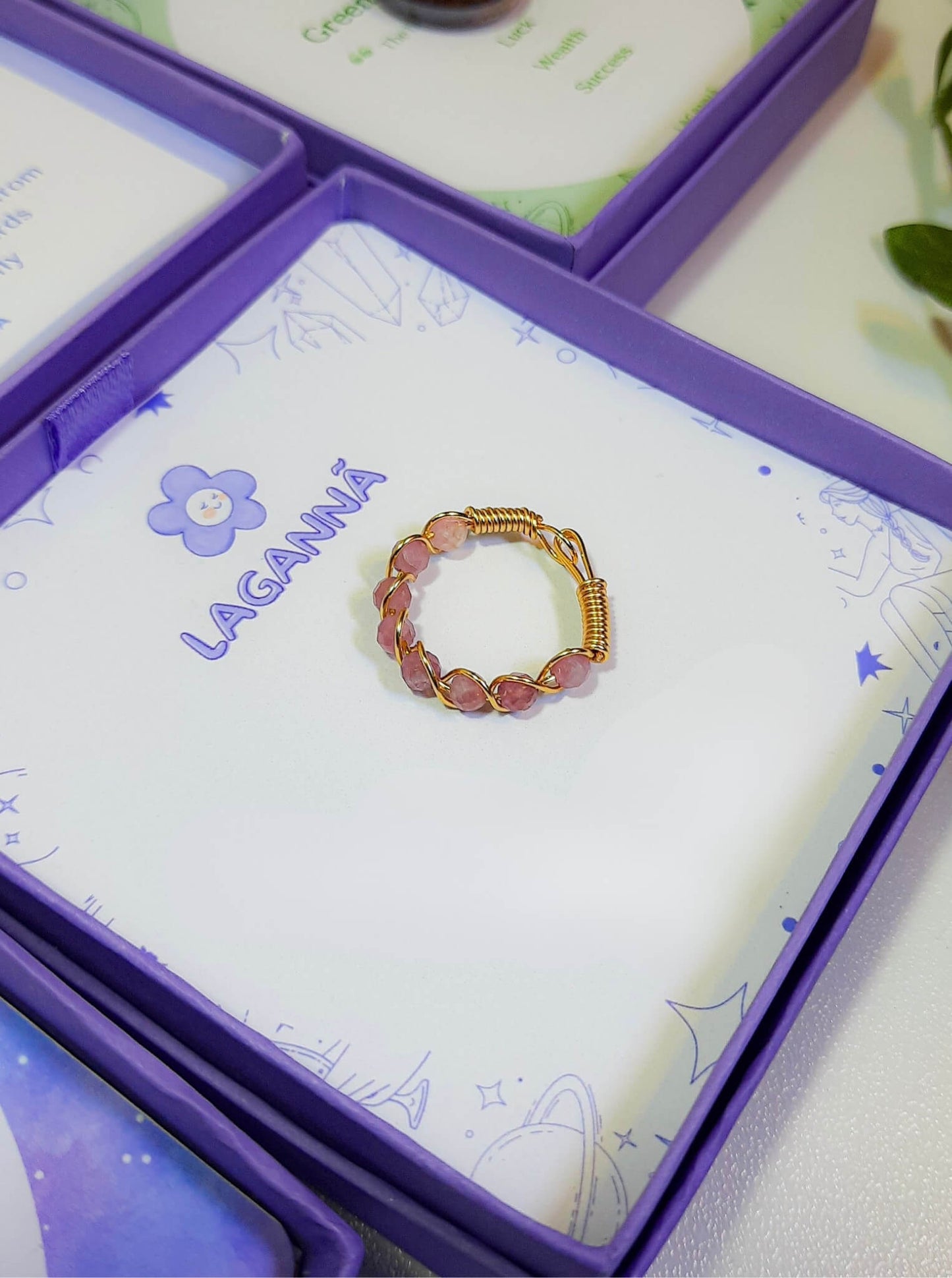 Pink tourmaline braided ring jewelry box closeup, handmade Sri Lankan gold wire wrapped healing crystal ring for happiness and emotional uplift