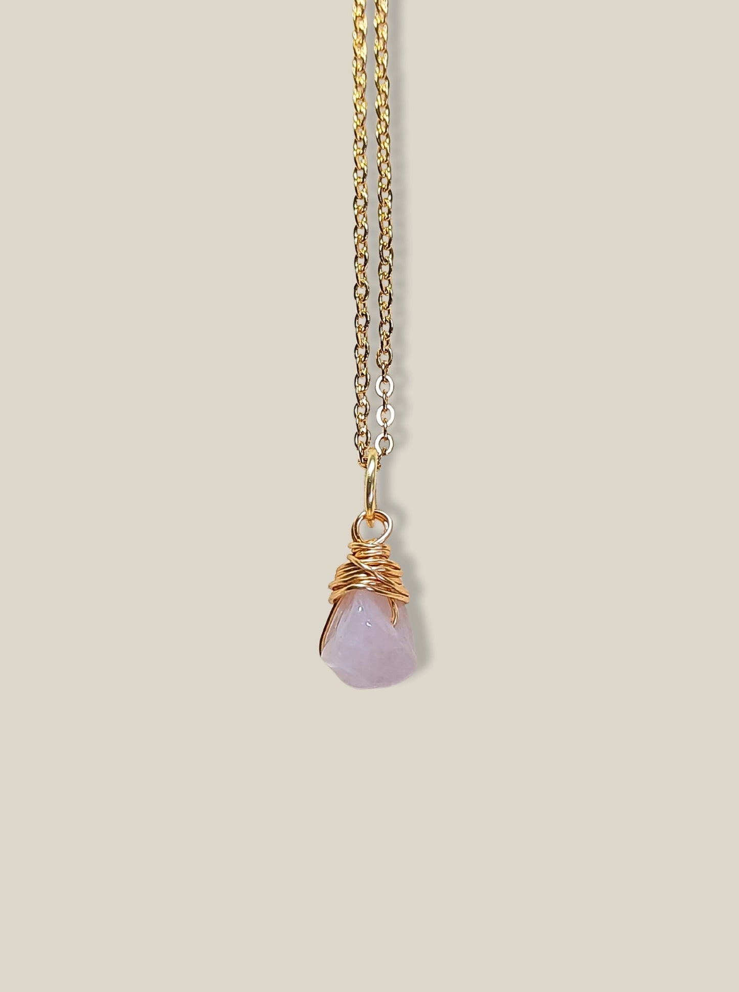 Rose quartz irregular stone necklace on light background showing gold wire wrapped design, handmade Sri Lankan healing crystal pendant for emotional healing
