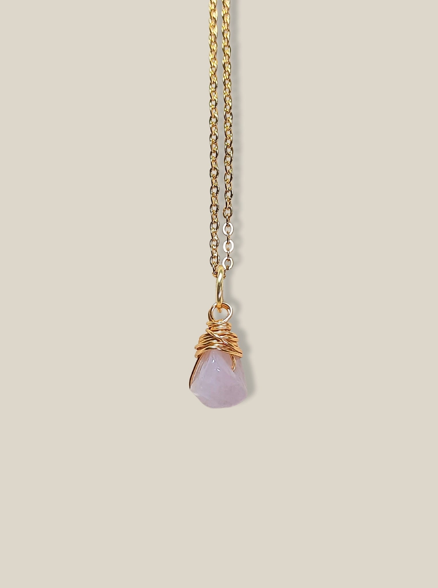 Rose quartz irregular stone necklace on light background showing gold wire wrapped design, handmade Sri Lankan healing crystal pendant for emotional healing