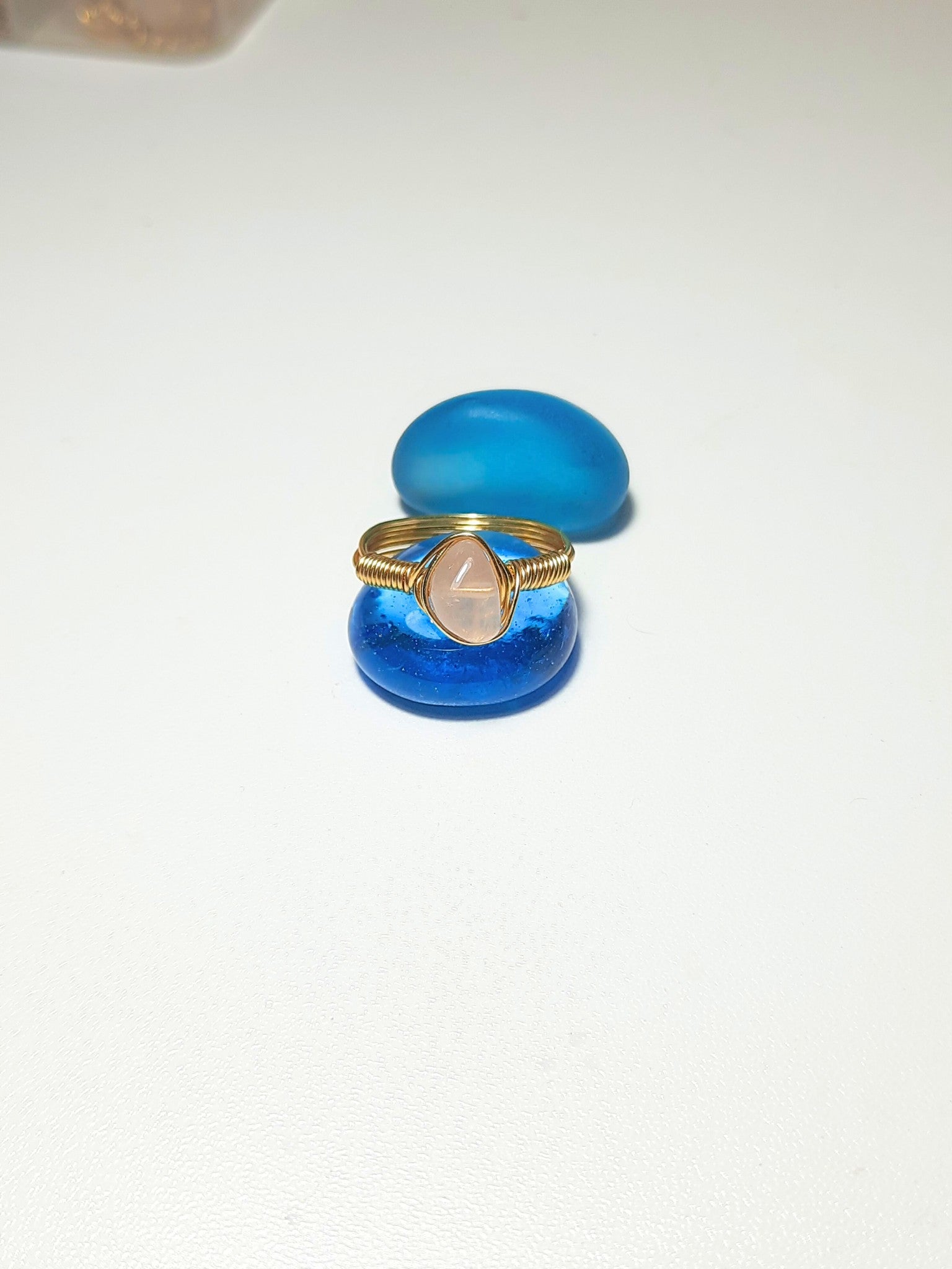 Rose quartz irregular stone ring on white background showing handmade gold wire wrapped healing crystal jewelry, Sri Lankan spiritual ring featuring natural pink gemstone perfect as boho love stone ring and protective amulet for emotional balance and self-love enhancement