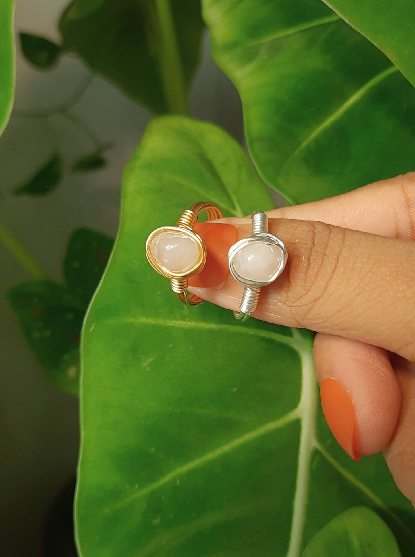 Rose quartz irregular stone rings holding on hand showing both gold and silver wire wrapped designs, handmade Sri Lankan healing crystal jewelry featuring natural pink gemstones perfect as boho love stone rings and heart chakra amulets for emotional balance and self-love lifestyle 