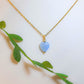 Handmade sweet heart blue chalcedony necklace in gold wire wrapped design with display stand and natural leaves showing healing crystal jewelry, Sri Lankan artisan throat chakra pendant featuring heart-shaped blue gemstone perfect as boho communication necklace and calming amulet for nature-loving jewelry enthusiasts
