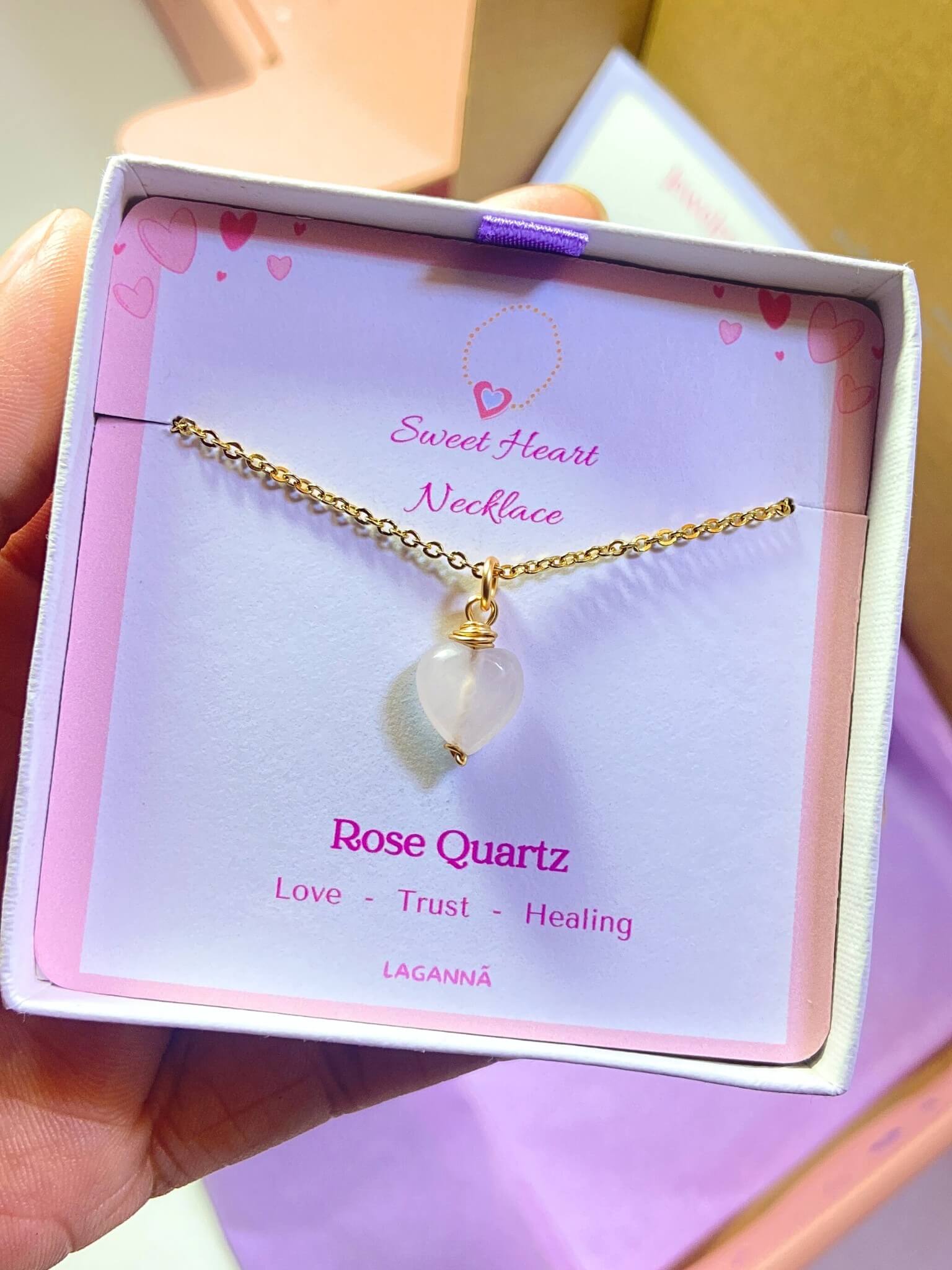 Sweet heart rose quartz necklace jewelry box held in hand showing handmade gold wire wrapped healing crystal gift set, Sri Lankan artisan heart chakra pendant featuring natural heart-shaped pink gemstone perfect as love jewelry gift for self-love and emotional healing with elegant presentation
