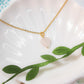 Sweet heart rose quartz necklace on white dish with natural leaves showing handmade gold wire wrapped healing crystal jewelry, Sri Lankan artisan heart chakra pendant featuring heart-shaped pink gemstone perfect as boho love necklace and self-love amulet for nature-loving jewelry enthusiasts