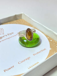 Handmade tiger's eye irregular stone ring in silver wire wrapped design on jewelry box featuring natural healing crystal jewelry crafted by Sri Lankan artisans as courage stone ring and solar plexus chakra balancing amulet for women seeking confidence and protection with raw golden brown gemstone energy