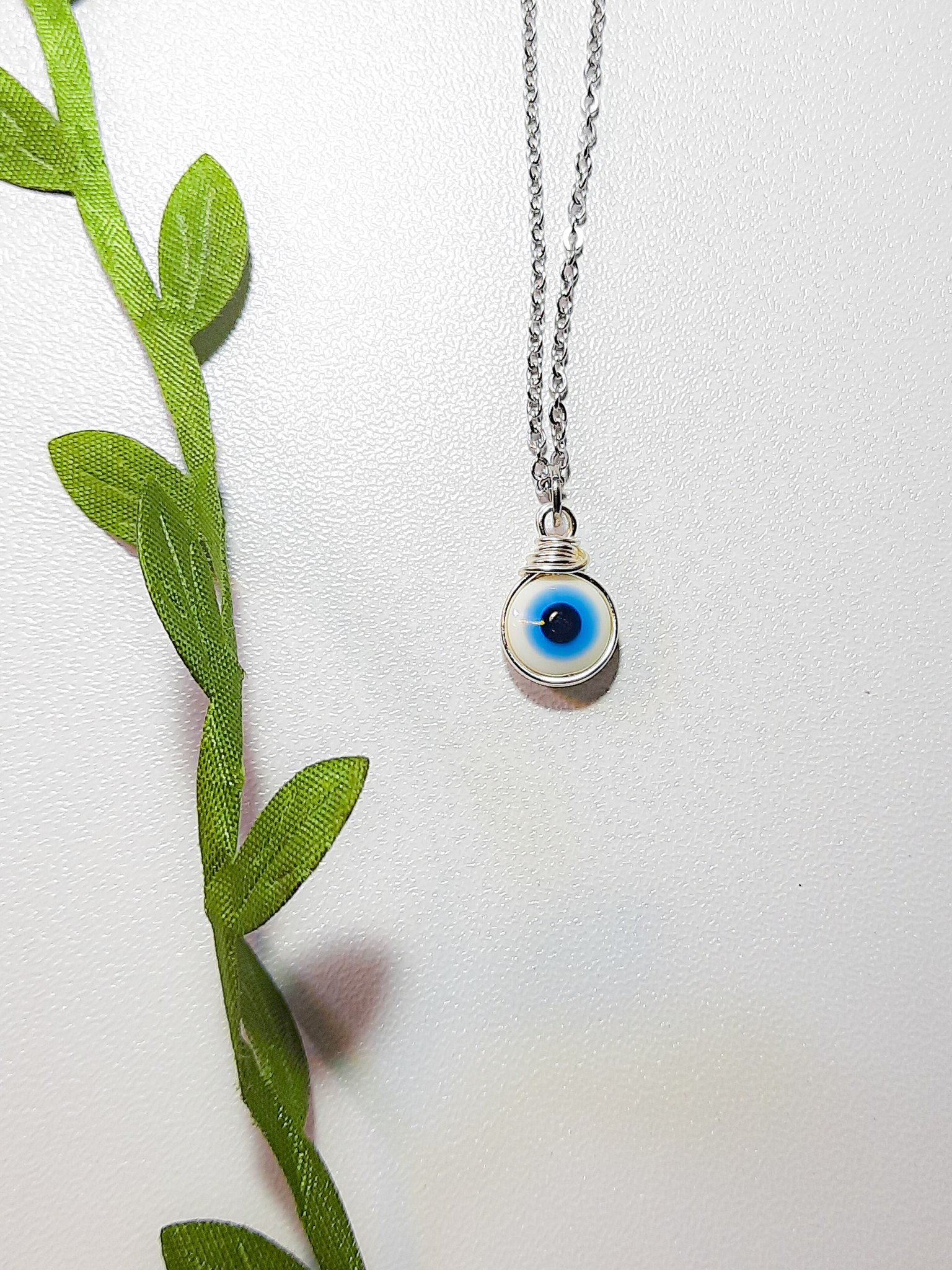 Laganna handmade white evil eye silver necklace for protection on light background